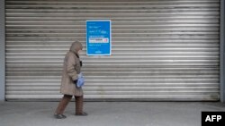 Una mujer pasa por una tienda por departamentos de la cadena minorista alemana Galeria del grupo Galeria Karstadt Kaufhof el 2 de abril de 2020 en Berlín, cerrada como la mayoría de las tiendas en una medida para limitar la propagación del nuevo coronavirus. 