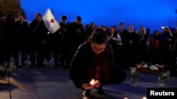 A woman places a candle with others at the Place Saint-Michel the day after Notre-Dame Cathedral suffered heavy damage from a massive fire that devastated large parts of the gothic structure in Paris, France, April 16, 2019. 