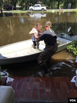 Graham Kinchen of St. Amant, Louisiana, takes time off to give his daughter a boat ride — in their front yard. (D. Kinchen/VOA)