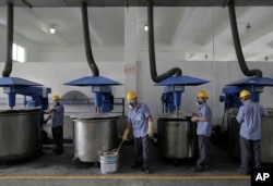 Workers in masks and safety helmets inspect mixing machines at GMM non-stick coatings factory in Zhuhai, Guangdong province, China, May 6, 2015.