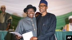 Le président Goodluck Jonathan du Nigeria, à gauche, et le candidat de l'opposition, le général Muhammadu Buhari, à droite, se tiennent main dans la main après avoir signé un renouvellement de leur engagement à organiser des élections pacifiques "libres, justes et crédibles", dans un hôtel dans le ...