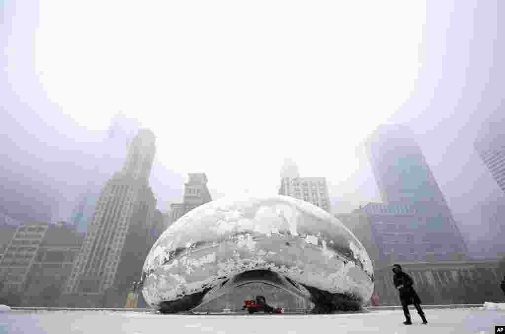 2013年3月5日，雪暴袭击芝加哥期间，一位女士走过&ldquo;云门&rdquo;雕塑。