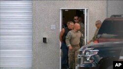 This frame grab from video provided by WPLG-TV shows FBI agents escorting Cesar Sayoc, in sleeveless shirt, in Miramar, Flordia, on Oct. 26, 2018. Authorities alleged Sayoc was the man who sent pipe bombs to some of President Donald Trump's most prominent critics.