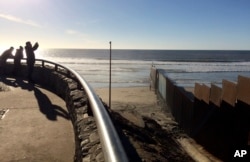 FILE - People look out toward where border structure separates San Diego, right, from Tijuana, Mexico, left, Jan. 25, 2017. President Donald Trump has moved aggressively to tighten the nation's immigration controls.