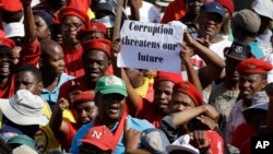 FILE - Protesters hold a placard demanding an end to corruption, at a rally in Pretoria, South Africa, Sept. 30, 2015.