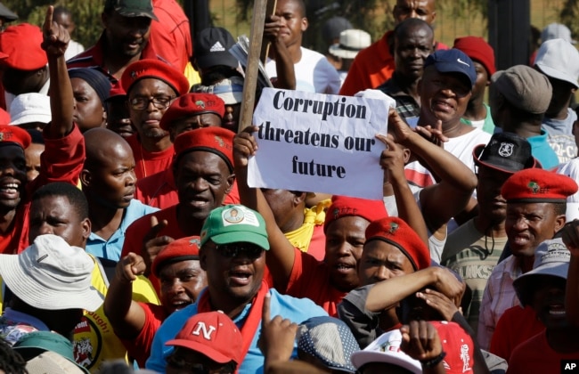 FILE - Protesters hold a placard demanding an end to corruption at a rally in Pretoria, South Africa, Sept. 30, 2015.