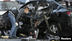 An investigator works near a car that was damaged by an explosion in central Kyiv, Ukraine, Sept. 8, 2017.