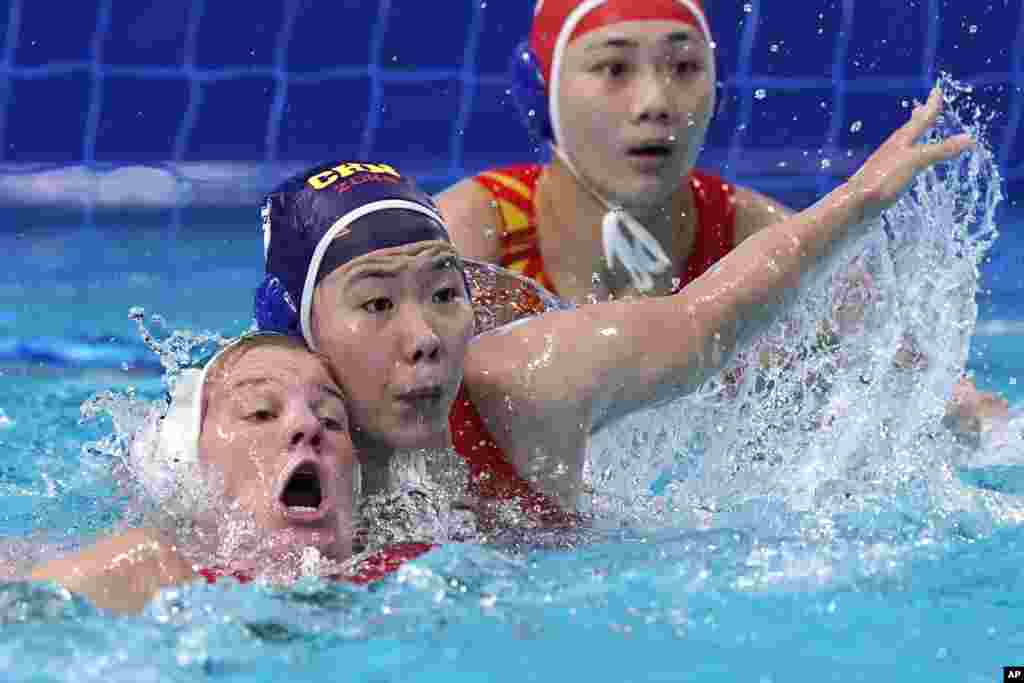 Hungary&#39;s Aniko Gyongyossy, left, and China&#39;s Wang Huan battle for position in front of China&#39;s goalkeeper Shen Yineng, right, during a preliminary round women&#39;s water polo match at the 2020 Summer Olympics in Tokyo, Japan.
