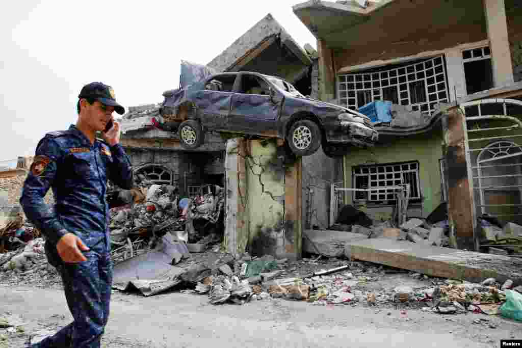 Seorang anggota Polisi Federal Irak berjalan di dekat rumah yang hancur pasca bentrokan dengan pejuang ISIS di wilayah timur Mosul, Irak.&nbsp;