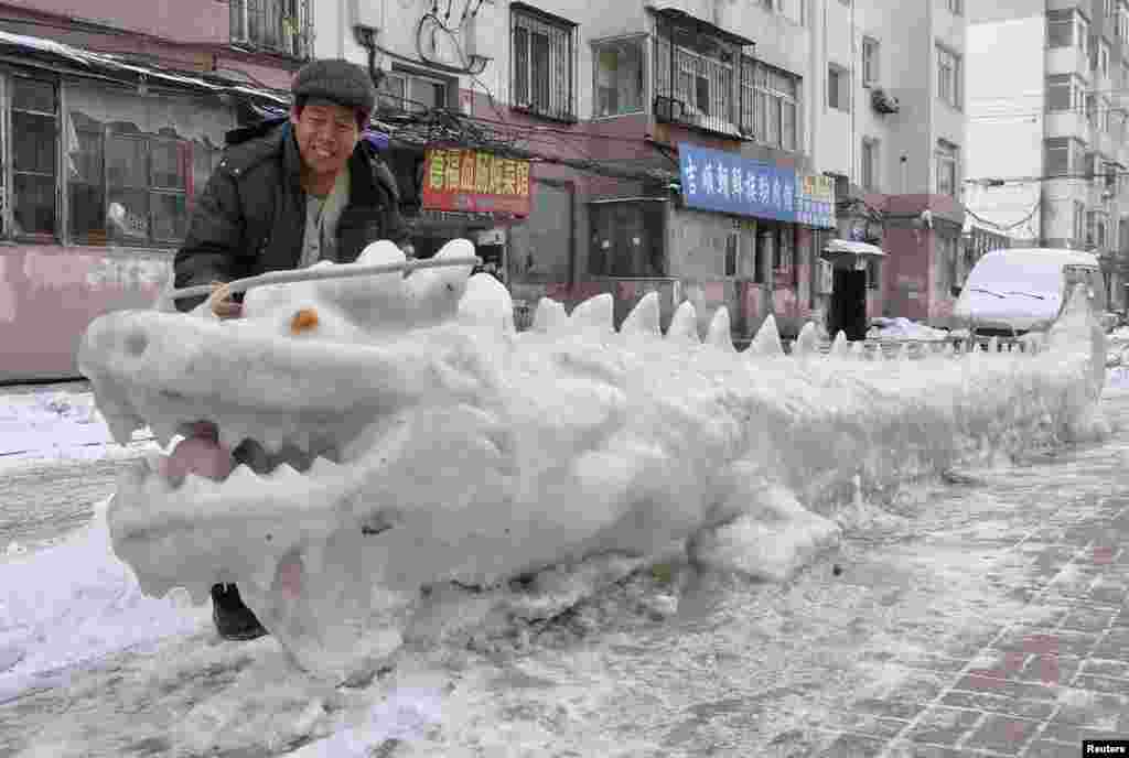 A man looks at a dragon-shaped snow sculpture made by local residents at a residential compound in Jilin, Jilin province, China.