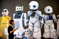 Seorang pengunjung berjalan melewati mural yang menampilkan robot dari pembuat robot China Canbot di Konferensi Robot Dunia di Beijing, Cina, Rabu, 15 Agustus 2018. (Foto: AP)