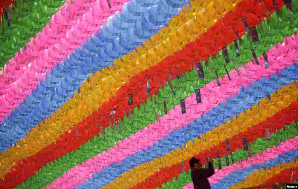 Seorang pekerja melampirkan kartu doa dan harapan yang berisi nama-nama pada lentera teratai dalam rangka persiapan hari kelahiran Sang Budha di Kuil Jogye di Seoul. Kelahiran Budha diperingati pada tanggal 6 Mei di Korea Selatan. &nbsp;