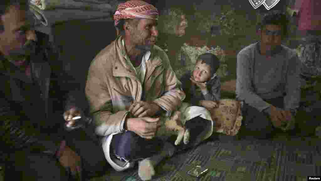 A refugee family from Kvromh village sit inside a makeshift house in the Serjilla archaeological site of Jabal al-Zawiya, Syria, March 29, 2014.