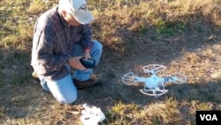 Don Hervig ties a meat lure to a quad-copter, to train his Apolmado falcon. (M. Osborne/VOA)