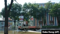 Une camionnette traverse les eaux de crue d'une rue inondée à Xinxiang, dans la province du Henan (centre de la Chine), le dimanche 25 juillet 2021. 