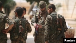 A U.S. fighter, who is fighting alongside Syria Democratic Forces (SDF), carries his national flag as he stands with SDF fighters in the northern province of Raqqa, Syria, May 27, 2016.