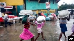 Yon gwoup fanm ki te kouvri tèt yo ak kivèt pou yo te ka sikile pandan yon lapli Siklòn Matthew tap lage sou Pòtoprrens, kapital Ayiti, nan jounen madi 4 oktòb 2016 la. 