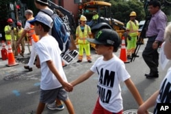 Construction workers watch as children hold hands during a march in protest of the separation of immigrant families, July 26, 2018, on Capitol Hill in Washington.