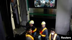 Passengers on the opposite side look at a damaged subway train as workers check it at a subway station in Seoul, May 2, 2014.
