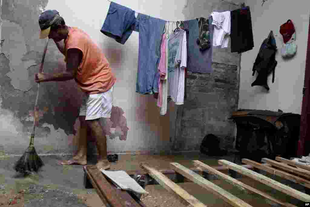 Jose Aguilera sweeps his home's floor by his empty bed frame after the passing hurricane Sandy damaged his roof, causing rain to soak his mattress, in Gibara, Cuba, October 25, 2012.