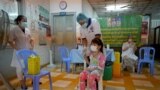 FILE - A girl receives a dose of the Sinovac Covid-19 coronavirus vaccine at a health centre in Phnom Penh on November 1, 2021, as Cambodia begins vaccinating children from aged five and older. (Photo by TANG CHHIN Sothy / AFP)