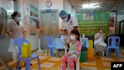 A girl receives a dose of the Sinovac Covid-19 coronavirus vaccine at a health center in Phnom Penh on November 1, 2021, as Cambodia begins vaccinating children from aged five and older. (Photo by TANG CHHIN Sothy / AFP)