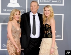 FILE - Glen Campbell, center, Kim Woolen, left, and Ashley Campbell arrive at the 54th annual Grammy Awards in Los Angeles, Feb. 12, 2012.