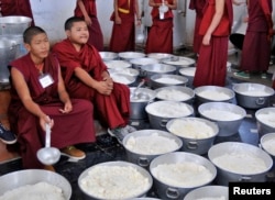 Young Buddhist monks wait to serve cooked rice to the attendees of the Jangchup Lamrim teachings conducted by the exiled Tibetan spiritual leader the Dalai Lama (unseen) at the Gaden Jangtse Thoesam Norling Monastery in Mundgod in the southern Indian state of Karnataka, Dec. 28, 2014.