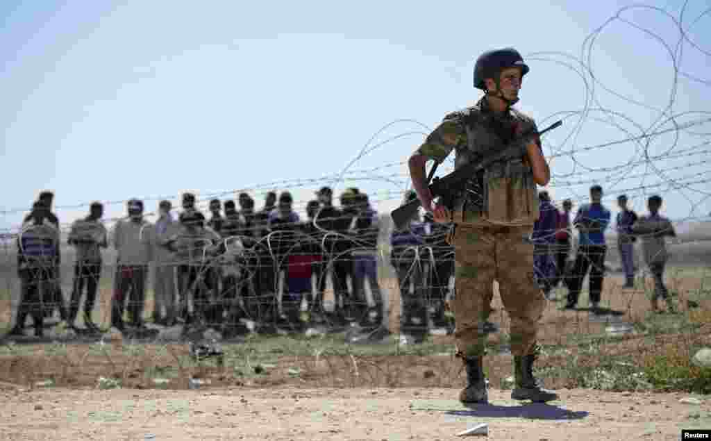 A Turkish soldier stands guard as Syrian Kurds wait behind the border fence near the southeastern town of Suruc in Sanliurfa province, September 21, 2014. Kurdish militants in Turkey have issued a new call to arms to defend a border town in northern Syria