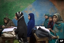 FILE - Afghan refugee schoolgirls attend a class at a makeshift school on the outskirts of Islamabad, Pakistan, Feb. 23, 2015.