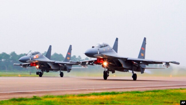 FILE - Two Chinese SU-30 fighter jets take off from an unspecified location to fly a patrol over the South China Sea, in this undated file photo released by China's Xinhua News Agency.