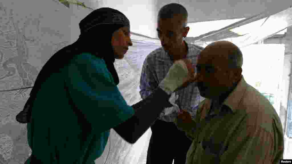 Aisha Masri helps a wounded man at Karaj al-Hajez crossing, a passage way separating Aleppo's rebel-controlled and regime-controlled neighborhoods, Sept. 23, 2013.