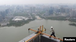 FILE - A worker walks on the roof of an office building construction site near a lake in Hefei, Anhui province.