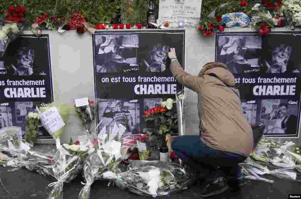 A person places flowers in front of the offices of weekly satirical paper Charlie Hebdo in Paris, Jan. 8, 2015.
