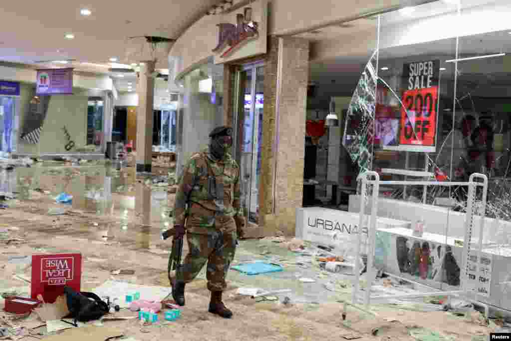 A member of the military inspects the damage at the looted Jabulani mall as the country deploys army to quell unrest linked to jailing of former President Jacob Zuma, in Soweto, South Africa.