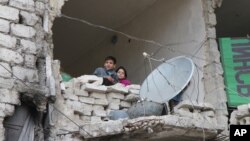 FILE - children peer from a partially destroyed home in Aleppo, Syria. 