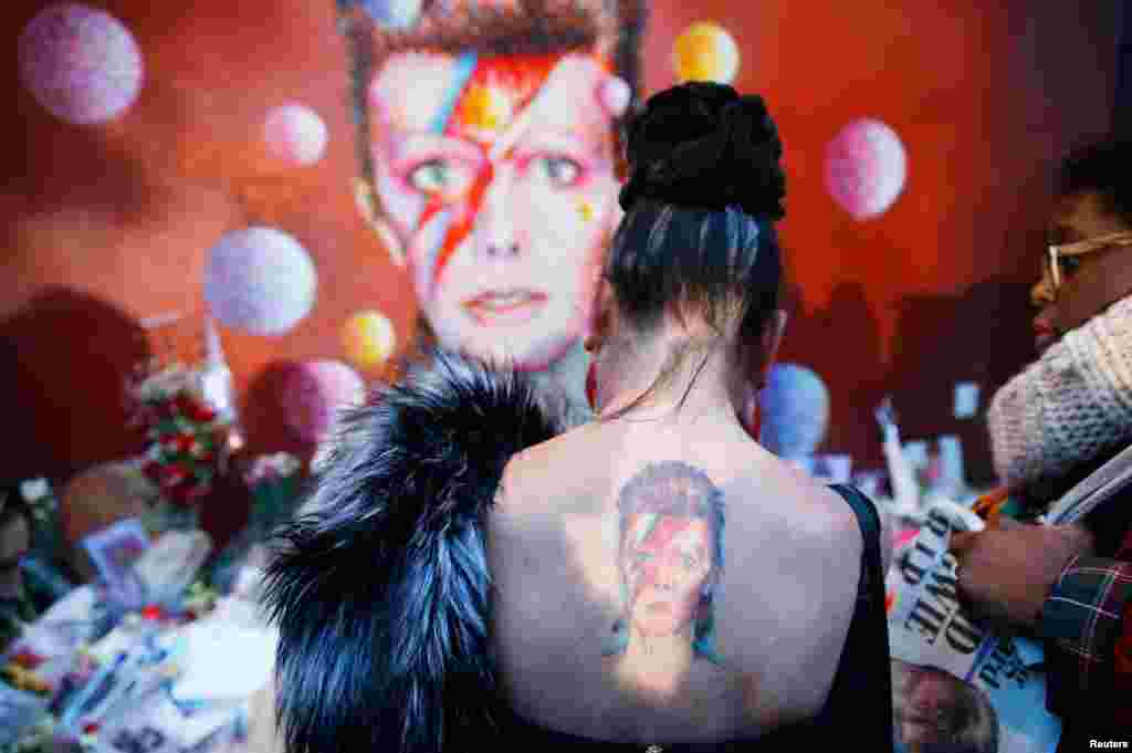 영국의 전설적인 록 가수 데이빗 보위가 암 투병 끝에 타계한 가운데, 영국 런던 남부에 있는 그의 벽화 앞에 추모객들이 모여있다. 추모객 중 한 여성의 등에 보위의 모습을 담은 문신이 보인다.