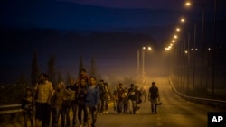 Syrian refugees walk along a road of the border town of Idomeni , northern Greece, to cross the border and enter Macedonia, Aug. 25, 2015.