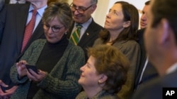 U.S. Senate Environment and Public Works Committee Chairman Sen. Barbara Boxer, D-Calif., left, checks her phone during a meeting of the Senate Climate Action Task Force prior to taking to the Senate Floor all night to urge action on climate change, March 10, 2014.