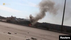 FILE - An armored vehicle rides next to a smoke as Syrian Democratic Forces affiliates clash with Islamic State militants outside a prison in Hassakeh, Syria, Jan. 22, 2022, in this screen grab taken from a video.