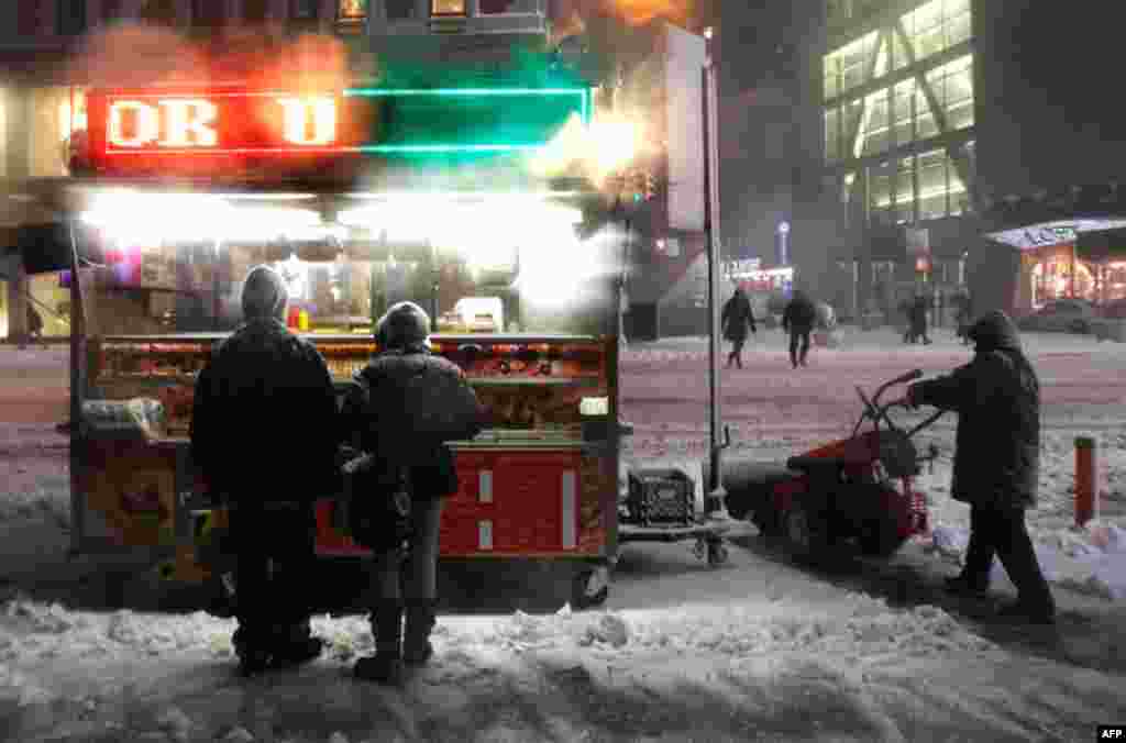 January 26: People wait to buy food from a stand as a man snowplows during a snowstorm in New York. (Reuters/Shannon Stapleton)