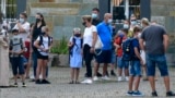 FILE - In this Wednesday, Aug. 12, 2020 file photo, parents wait with children on the schoolyard for the start of their first day at a school in Gelsenkirchen, Germany. (AP Photo/Martin Meissner, File)