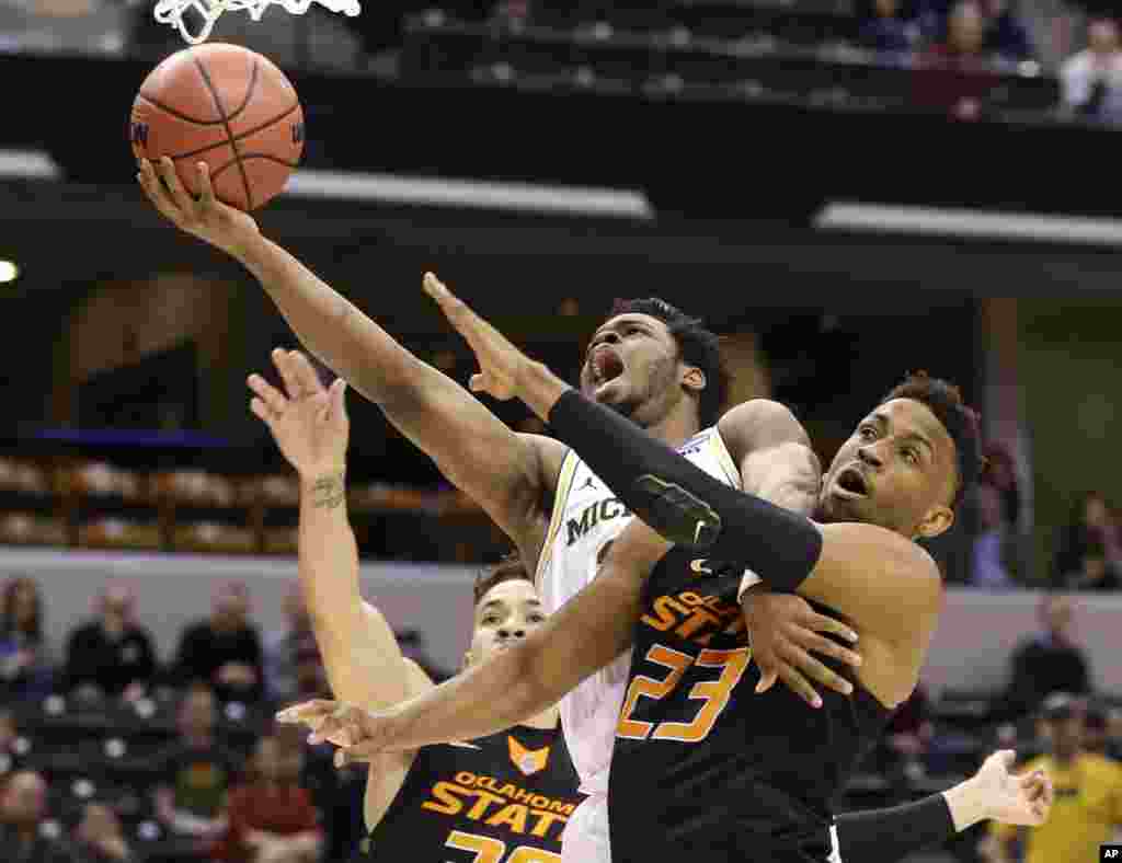 University of Michigan guard Derrick Walton Jr. (10) is fouled as he shoots by Oklahoma State University forward Leyton Hammonds (23) during a first-round game in the men&#39;s NCAA college basketball tournament in Indianapolis, Indiana.