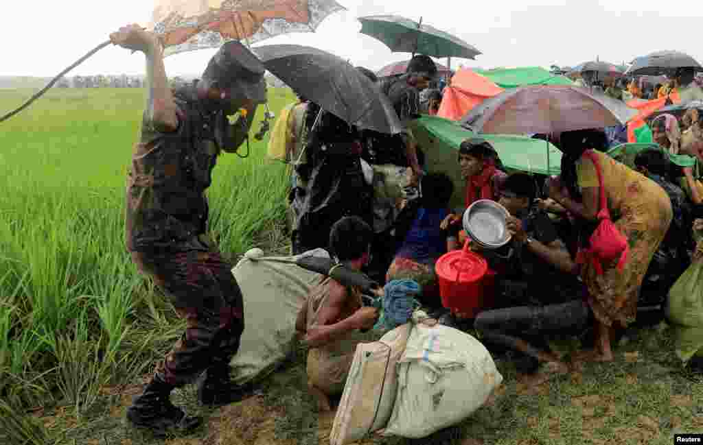 A Bangladesh border guard tries to control Rohingya refugees after denying them to move further, in Palang Khali, Bangladesh.