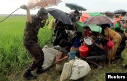 A Bangladesh border guard tries to control Rohingya refugees after denying them to move further, in Palang Khali, Bangladesh, Oct. 16, 2017.