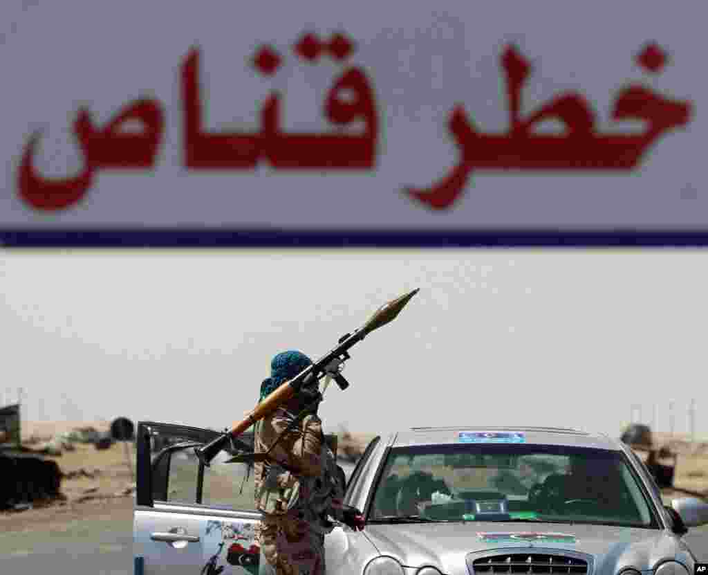 A rebel fighter holds a rocket launcher behind a banner that reads "Dangerous Sniper", at the frontline along the western entrance of Ajdabiya, April 23, 2011. (Reuters image)