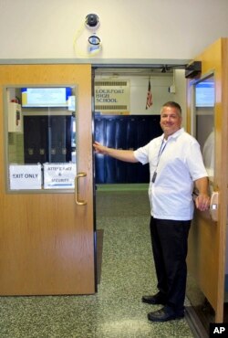 In this July 10, 2018 photo, District technology director Robert LiPuma stands in a doorway beneath a camera with facial recognition capabilities that is being installed in Lockport High School in Lockport, N.Y. (AP Photo/Carolyn Thompson)