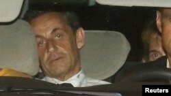 Cựu tổng thống Pháp Nicolas Sarkozy đi cùng cảnh sát tới đơn vị điều tra tài chính ở Paris để trình diện trước một thẩm phán cuối ngày 1/7/2014. 