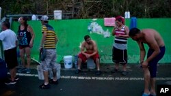 People affected by Hurricane Maria wait in line to collect water piped from a creek in the mountains, in Naranjito, Puerto Rico, Sept. 28, 2017. Residents of the area drive to the pipes to bathe because they were left without water by the damage caused by Hurricane Maria. The pipe was set up by a neighbor who ran it from a creek in his property to the side of the road in order to help those left without water. 