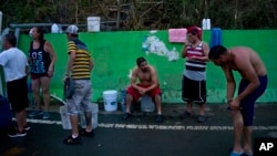 People affected by Hurricane Maria wait in line to collect water piped from a creek in the mountains, in Naranjito, Puerto Rico, Sept. 28, 2017. Residents of the area drive to the pipes to bathe because they were left without water by the damage caused by Hurricane Maria. The pipe was set up by a neighbor who ran it from a creek in his property to the side of the road in order to help those left without water. 